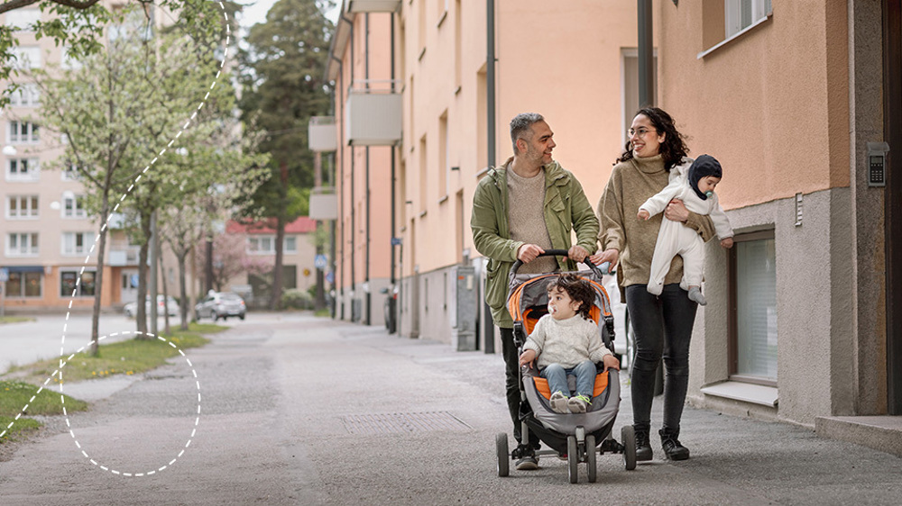 Familj promenerar med barnvagn och hund längs bostadsgata.